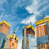 Skyscrapers construction site for modern buildings in New York  Cranes and scaffolding used to build tall structures, blue sky on background 