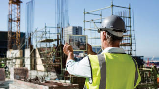 Rear view of male architect photographing construction site through digital tablet